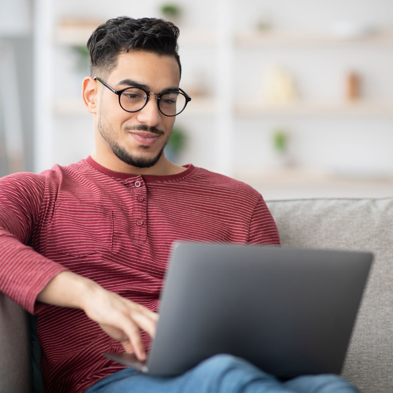 a man sitting on his couch with his laptop reading a blog