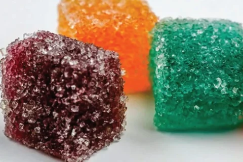 Colorful sugar-coated cannabis gummies on a white background